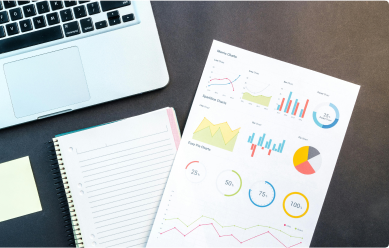 Graphs, a notebook, and a laptop on a desk